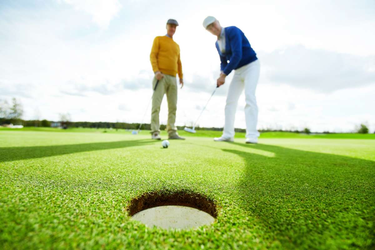 One of two active buddies going to hit golf ball by club while playing at leisure