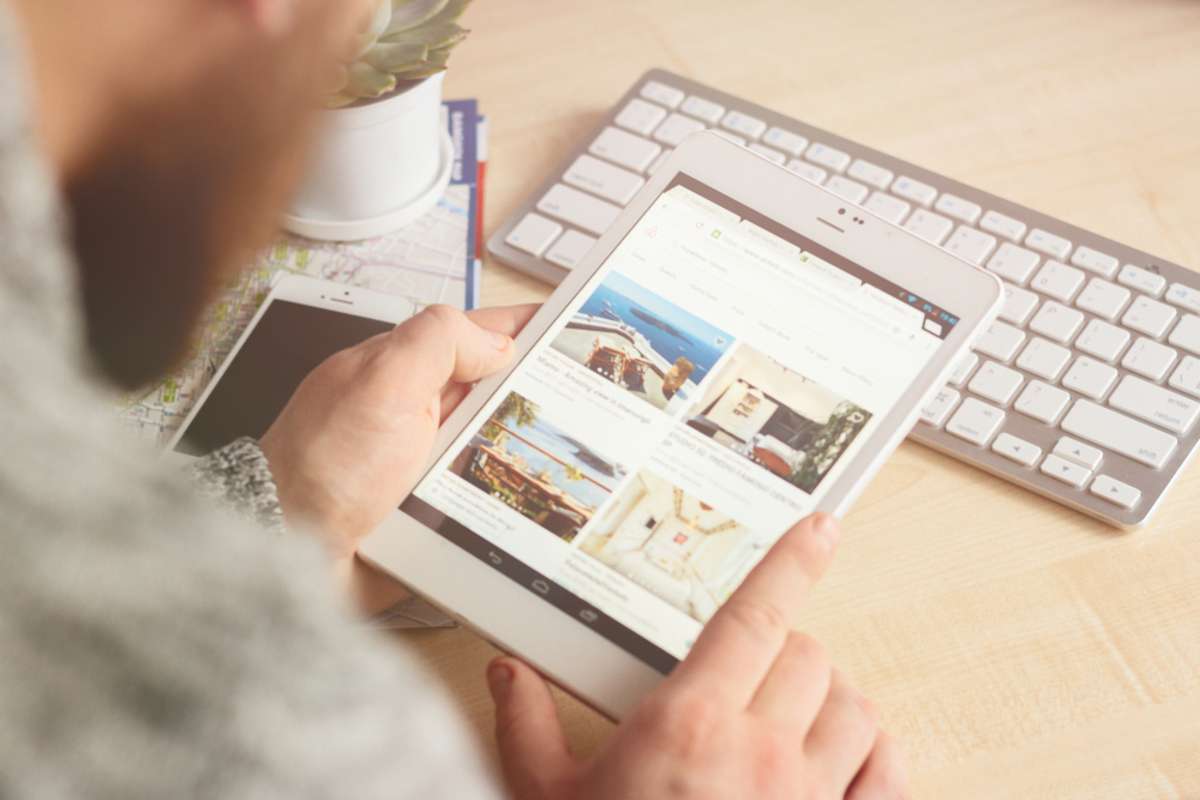 The mans hands with tablet searching and booking an appartments on Airbnb website