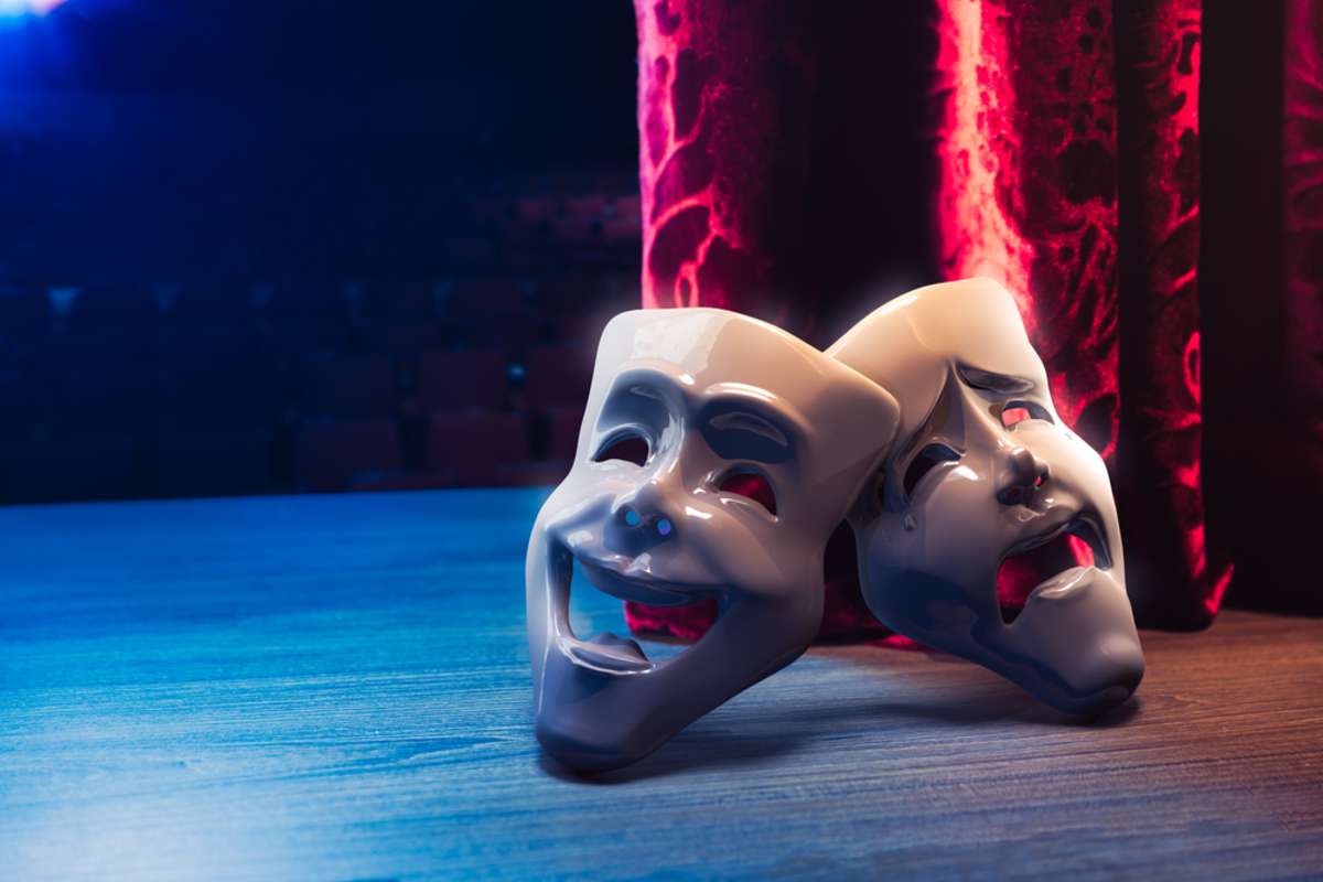 Theater masks, drama and comedy with a red curtain as backdrop